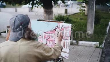 街头艺术家画一幅风景画。 从艺术家后面看。
